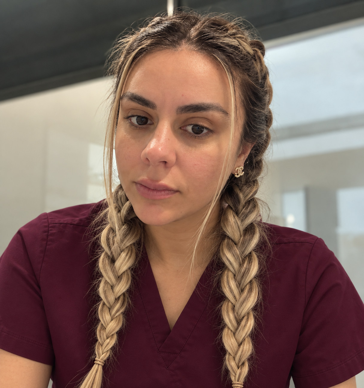 Mel Naghmeh with braided hair wearing burgundy scrubs in her clinic
